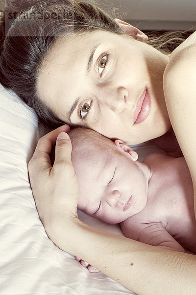 Mutter auf dem Bett liegend mit Neugeborenem  Portrait
