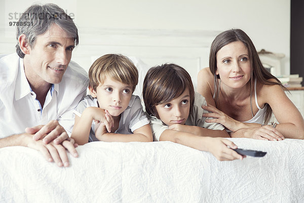 Familie beim Fernsehen im Bett  Porträt