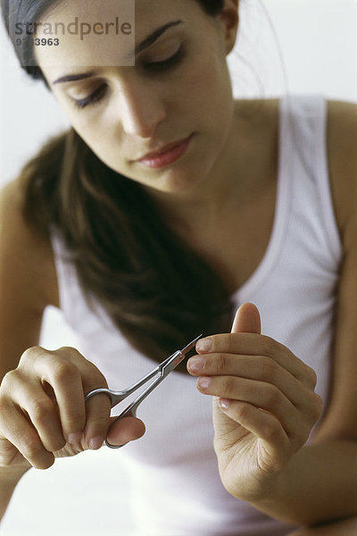 Junge Frau schneidet Fingernägel mit Nagelschere  Nahaufnahme