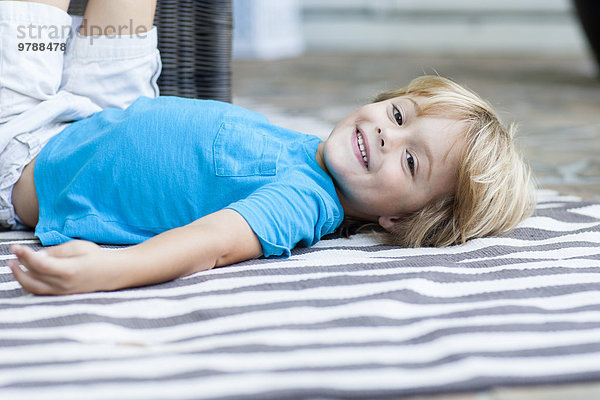liegend liegen liegt liegendes liegender liegende daliegen Europäer lächeln Junge - Person Teppichboden Teppich Teppiche