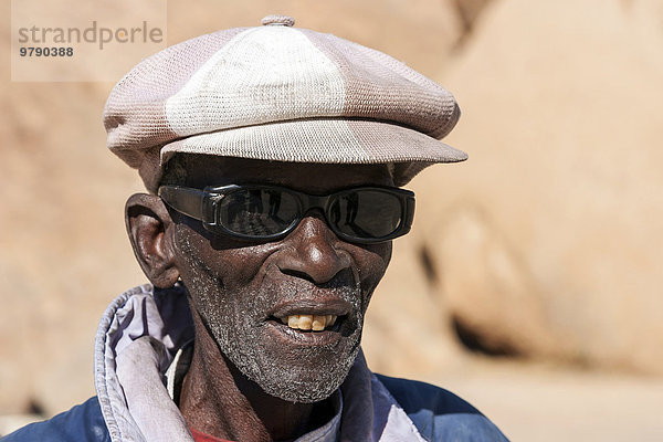 Einheimischer Mann mit Sonnenbrille und Mütze  Portrait  bei Spitzkoppe  Namibia  Afrika