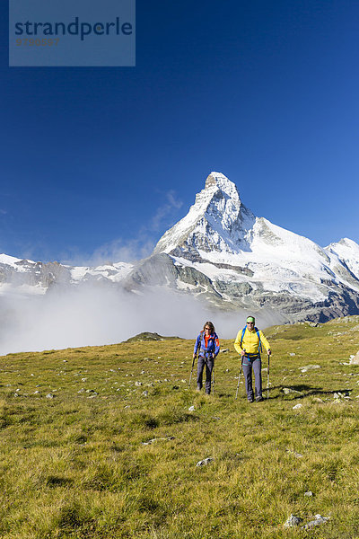 Eine Frau und ein Mann beim Wandern am Wanderweg Höhbalmen  dahinter das Matterhorn  Zermatt  Wallis  Schweiz  Europa