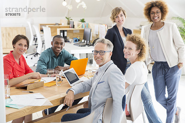 Gruppenporträt von lächelnden Büroangestellten am Tisch