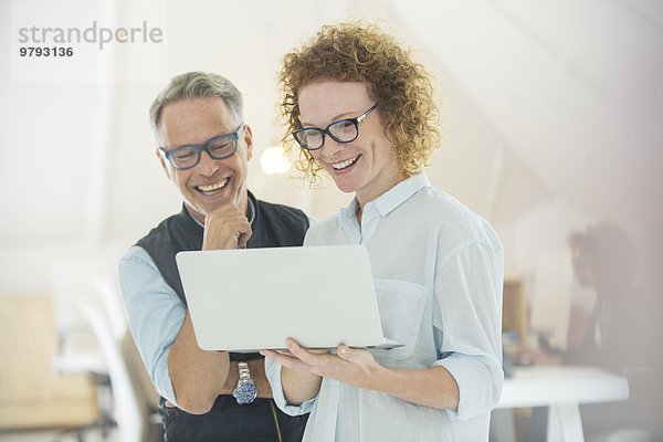 Zwei lächelnde Büroangestellte mit Laptop