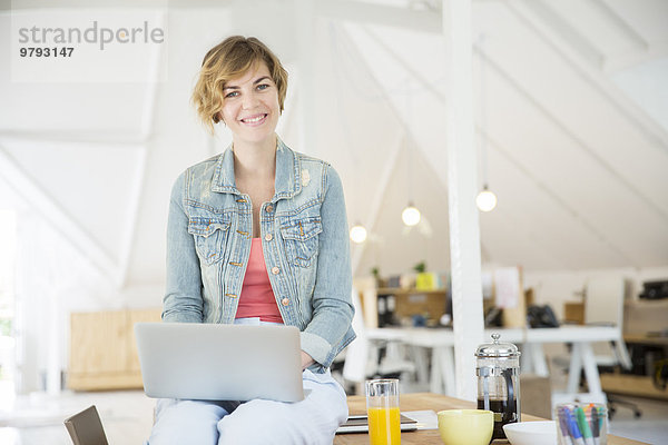 Büroangestellte mit Kaffee am Laptop