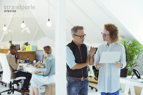 Zwei lächelnde Büroangestellte mit Laptop