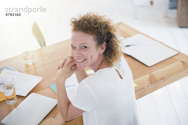 Porträt eines jungen lächelnden Büroangestellten am Schreibtisch