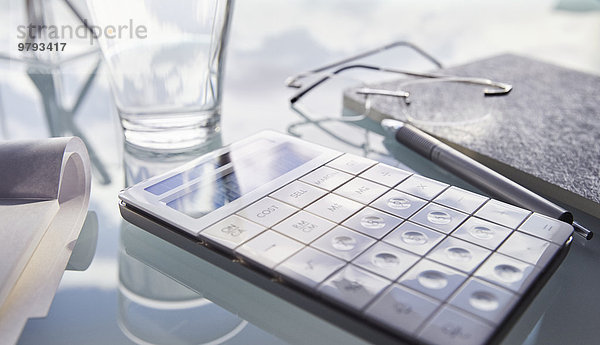 Nahaufnahme von Schreibtisch mit Taschenrechner  Glas  Stift und Notizblock