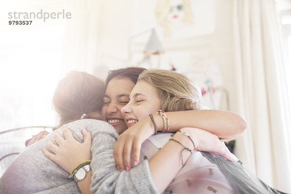 Drei Teenager-Mädchen  die sich zu Hause umarmen