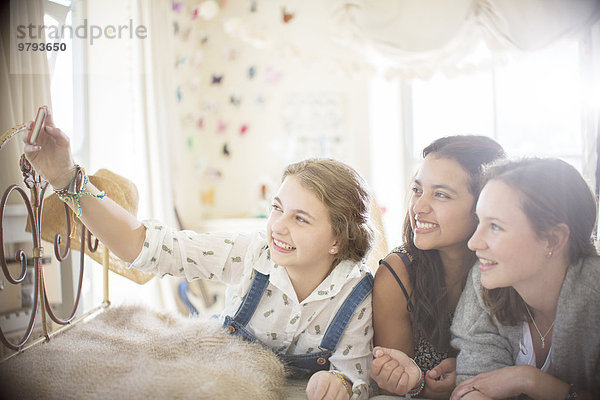 Drei Teenager-Mädchen  die Selfie im Bett im Schlafzimmer nehmen