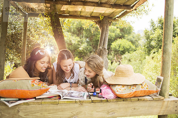 Drei Teenager-Mädchen beim Lesen im Sommer im Baumhaus