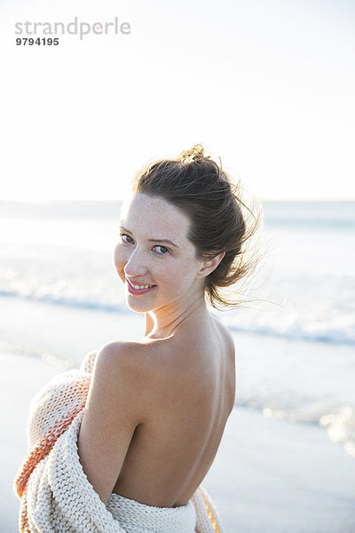 Porträt einer jungen Frau in Decke gehüllt am Strand