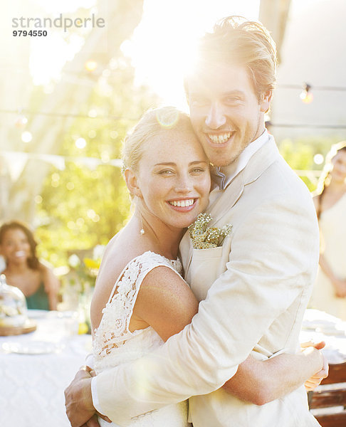 Porträt eines jungen Paares  das sich während der Hochzeitsfeier im Garten umarmt.