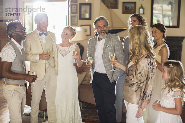 Junges Paar mit Gästen und Champagnerflöten bei der Hochzeitsfeier