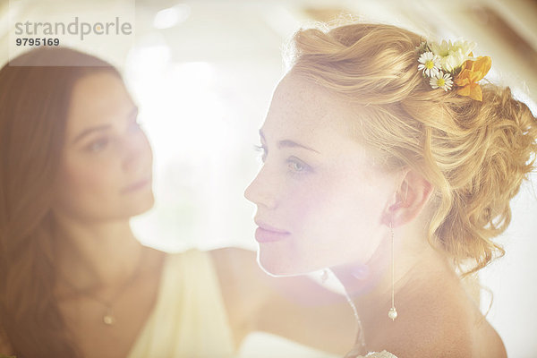 Portrait der Braut mit Brautjungfer im Hintergrund im Wohnzimmer