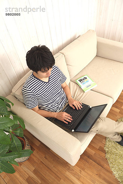 Mann Notebook Couch arbeiten jung japanisch