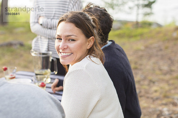 Porträt einer glücklichen Frau mit Freunden am Picknicktisch