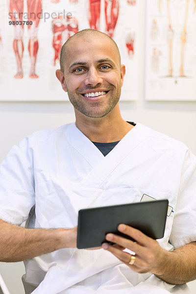 Porträt eines glücklichen Arztes mit digitaler Tablette in der orthopädischen Klinik
