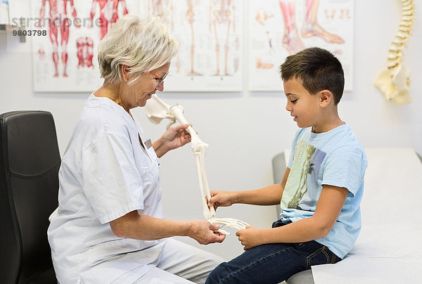 Senior-Orthopädin zeigt dem Jungen in der Klinik das Handmodell