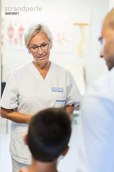 Senior-Orthopädin im Gespräch mit der Familie in der Klinik