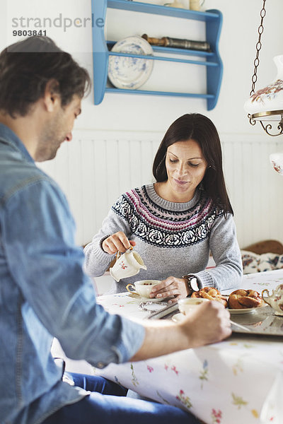 Mittlere erwachsene Frau mit Mann beim Frühstück am Tisch
