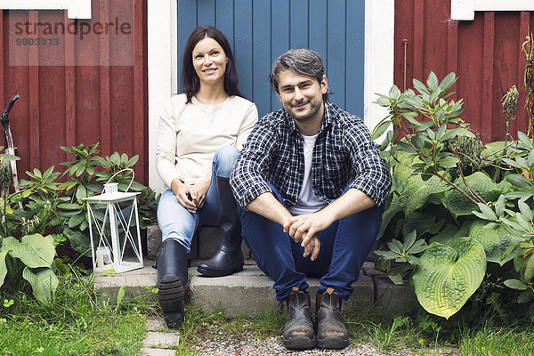 Porträt des lächelnden erwachsenen Paares vor dem Bauernhaus