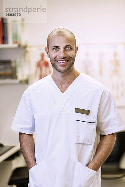 Portrait eines lächelnden orthopädischen Chirurgen mit Händen in den Taschen in der Klinik