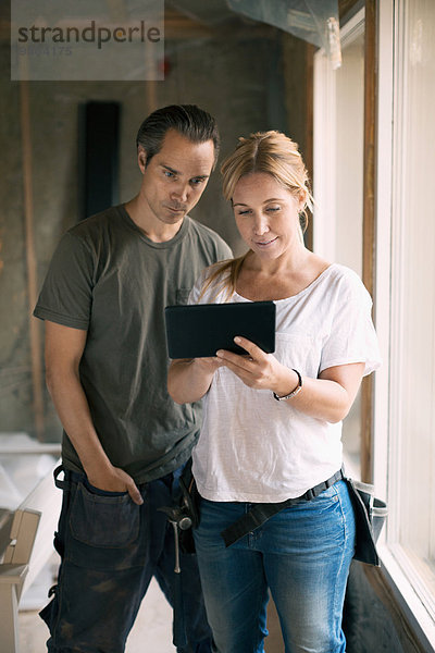 Paar mit digitalem Tablett im renovierten Haus
