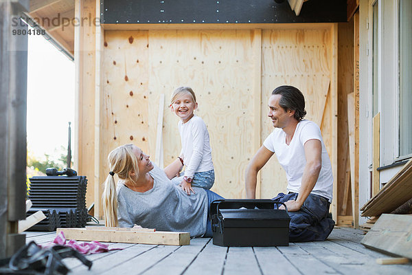 Glückliche Familie mit Werkzeugkasten vor dem Haus