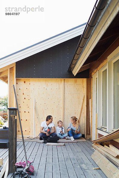 Glückliche Familie mit Bauwerkzeugen vor dem Haus