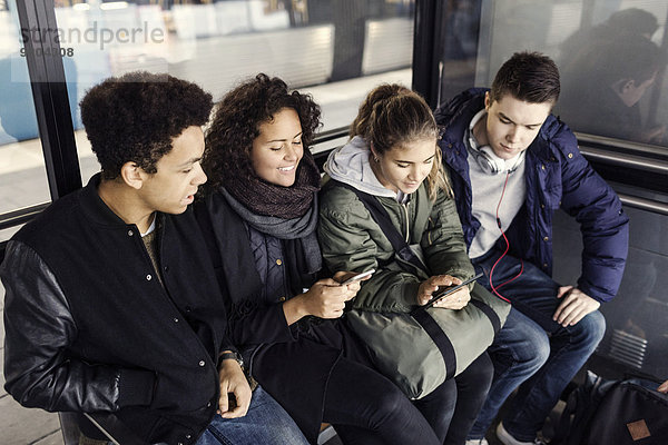Studenten mit Smartphone und digitalem Tablett an der U-Bahn-Station
