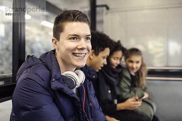 Fröhlicher Student sitzt mit Freunden an der U-Bahn-Station