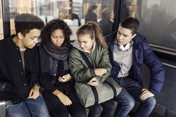 Universitätsstudenten nutzen gemeinsam Smartphone an der U-Bahn-Station