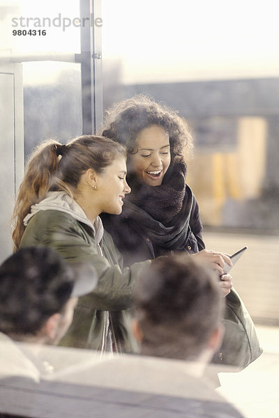 Zufriedene Studentinnen mit digitalem Tablett in der U-Bahn-Station