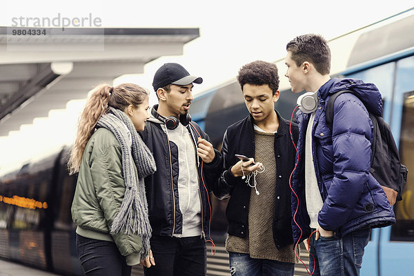 Multi-ethnische Universitätsstudenten mit Smartphone in der U-Bahn-Station