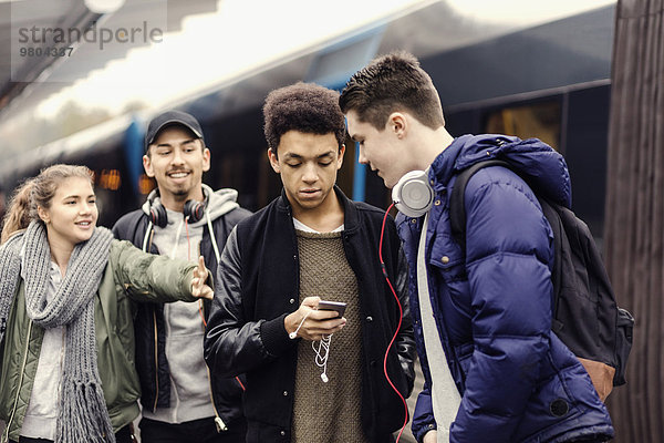 Junge Frau ruft Freunde über Smartphone in der U-Bahn-Station an