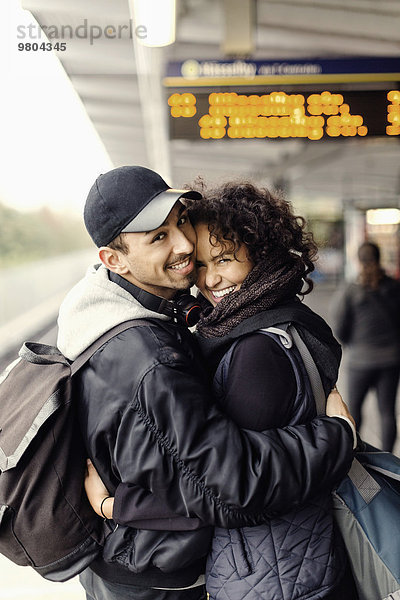 Seitenansicht Porträt eines glücklichen Paares  das sich in der U-Bahn umarmt.