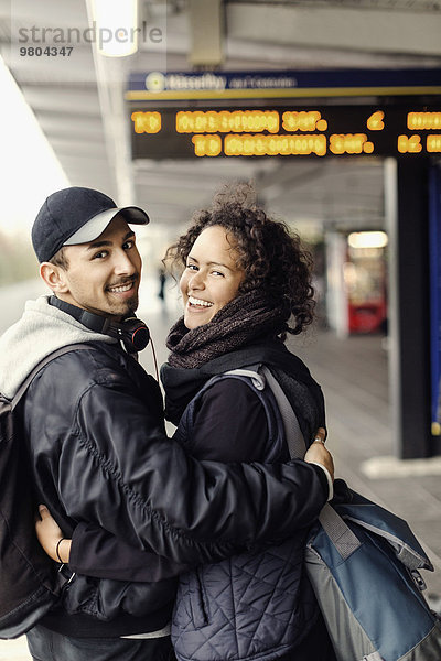 Seitenansicht Porträt eines glücklichen Paares mit Armen auf dem U-Bahn Bahnsteig