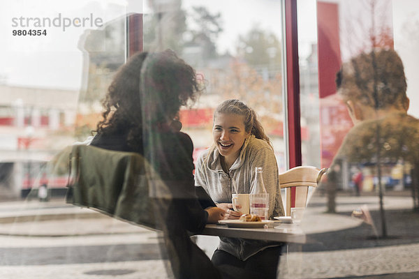 Blick auf glückliche Studenten im Cafe durch Glas