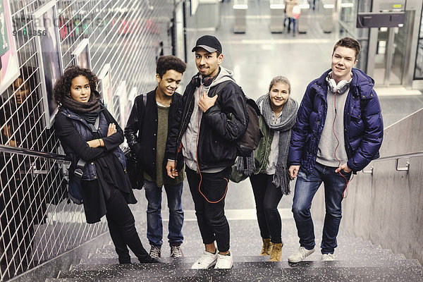 Ganzflächiges Porträt von Universitätsstudenten  die auf Stufen an der U-Bahn-Station stehen.