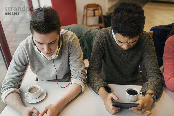 Männliche Universitätsstudenten mit digitalem Tablett am Kaffeetisch