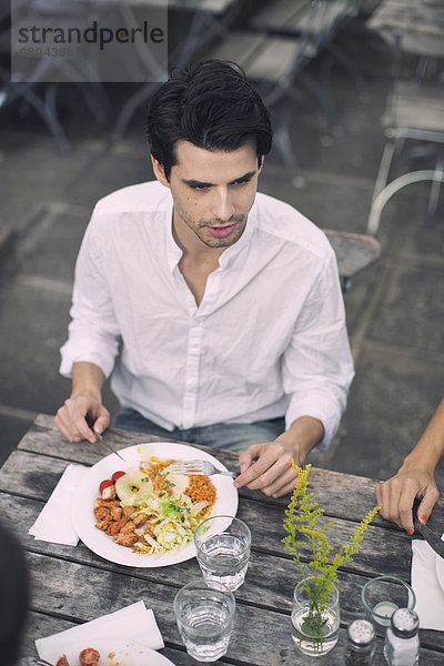 Mann beim Mittagessen mit Freund im Outdoor-Café