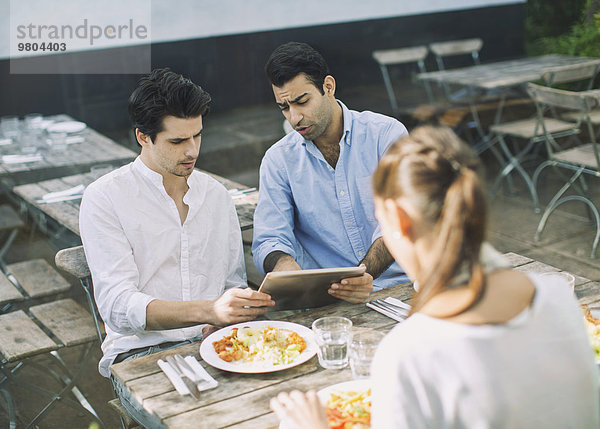 Seriöse Männer mit digitalem Tablett im Outdoor-Café