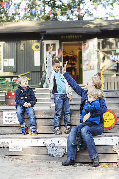 Fröhliche Lehrerin gibt High-Five außerhalb des Vorschulgebäudes