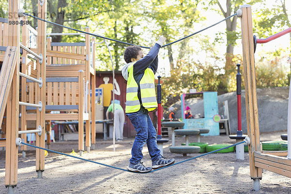 Seitenansicht des Jungen beim Balancieren am Seil auf dem Spielplatz