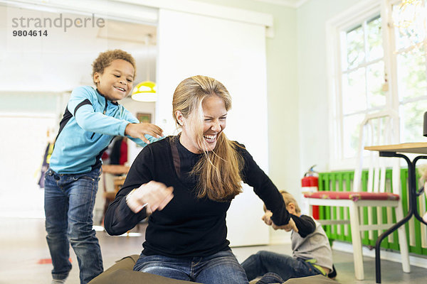 Glückliche Lehrerin beim Spielen mit Jungen im Kindergarten