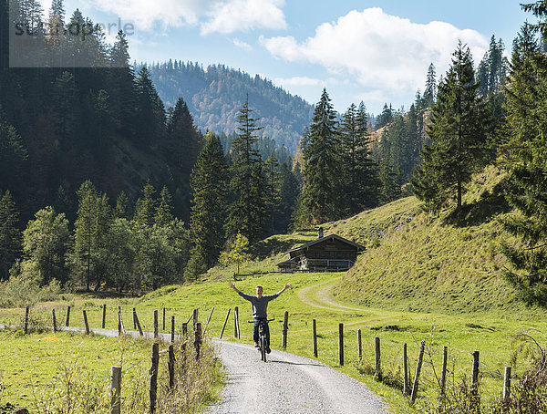 Junger Mann fährt freihändig Fahrrad  Berglandschaft  Valepptal  Spitzingsee  Bayern  Deutschland  Europa