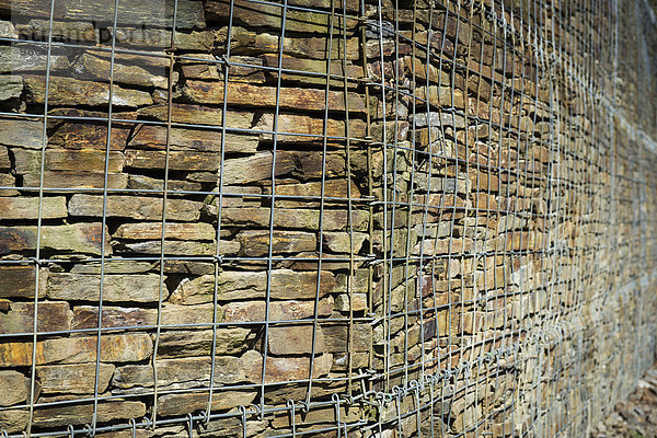 Mauer mit aufgeschichteten Steinen hinter Stahlgitter