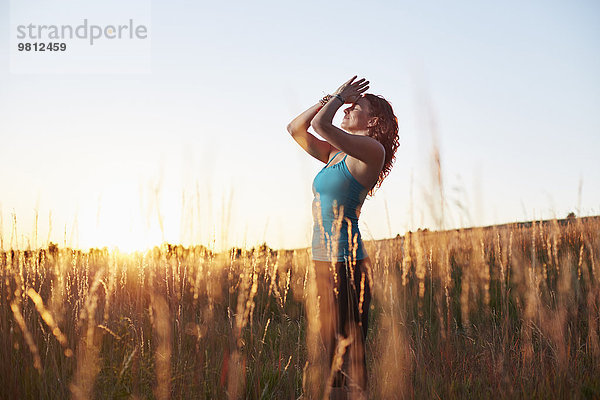 Reife Frau beim Yoga auf dem Feld