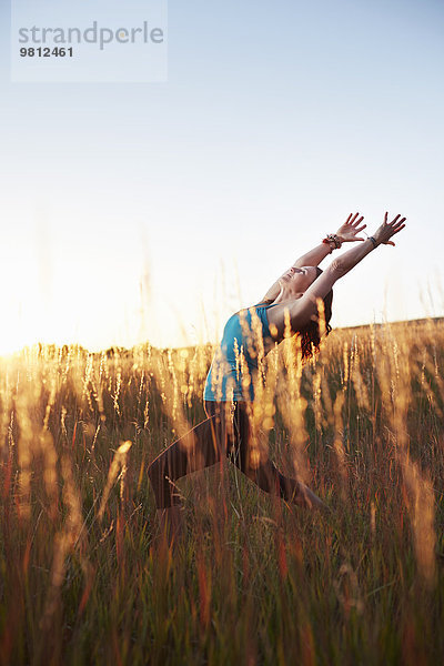 Reife Frau beim Yoga auf dem Feld